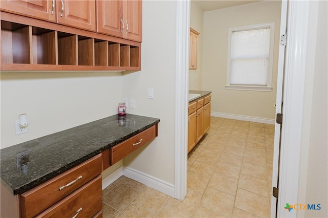 kitchen featuring built in desk and dark stone counters