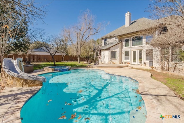 view of swimming pool featuring a water slide, a patio, and an in ground hot tub