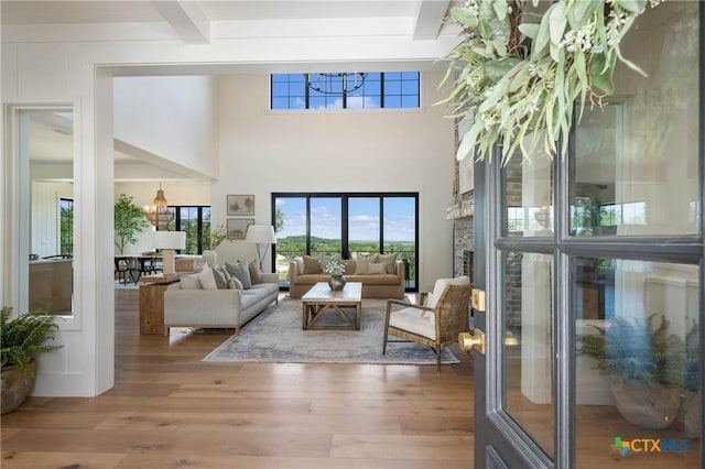 living room featuring a towering ceiling, wood finished floors, and beamed ceiling