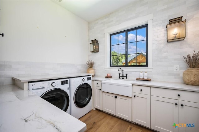 laundry area featuring cabinet space, independent washer and dryer, light wood-style flooring, and a sink