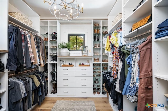 walk in closet featuring wood finished floors and an inviting chandelier