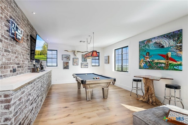 recreation room featuring billiards, wood finished floors, visible vents, baseboards, and brick wall