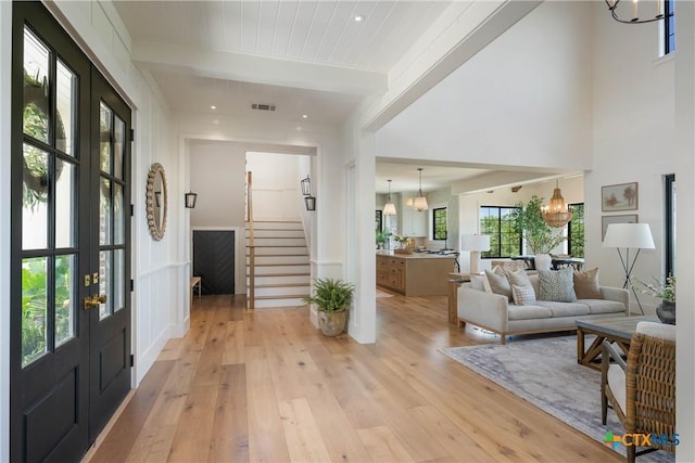 entrance foyer featuring stairway, an inviting chandelier, visible vents, and light wood-type flooring