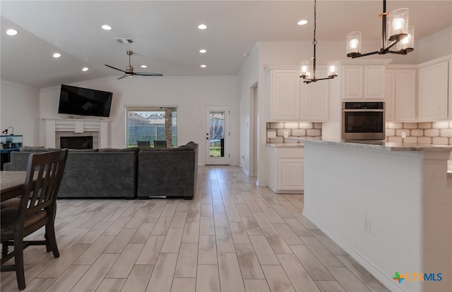 kitchen with white cabinetry, oven, decorative light fixtures, and crown molding