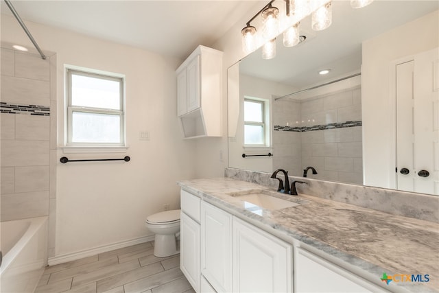 full bathroom featuring vanity, tiled shower / bath combo, and toilet