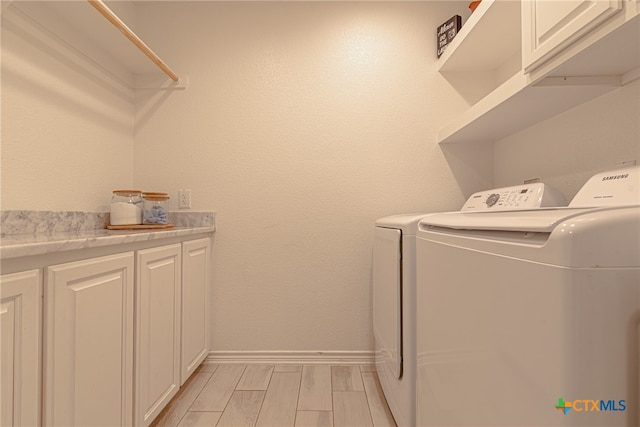 clothes washing area with cabinets and washing machine and dryer