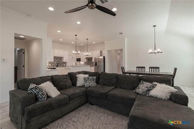 living room with light wood-type flooring, ceiling fan with notable chandelier, and crown molding