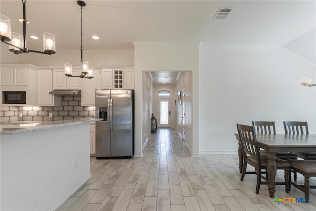 kitchen with light stone counters, light wood-type flooring, pendant lighting, stainless steel refrigerator with ice dispenser, and white cabinets