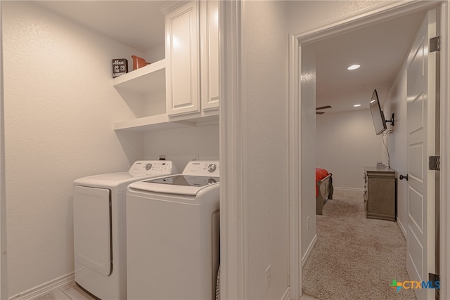 washroom with washer and clothes dryer, light carpet, and cabinets