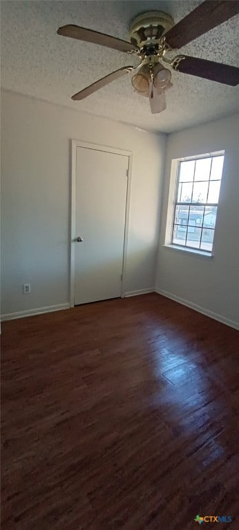 empty room with a textured ceiling, ceiling fan, and dark wood-type flooring