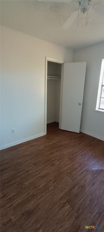 unfurnished bedroom with ceiling fan, a closet, and dark wood-type flooring