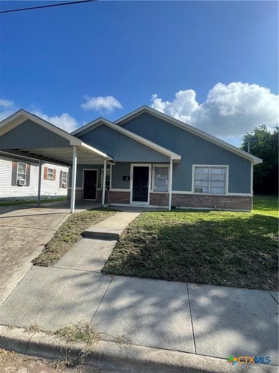 704 E 2nd St, Victoria, TX 77901 - ranch-style house with a carport, brick siding, a front lawn, and concrete driveway