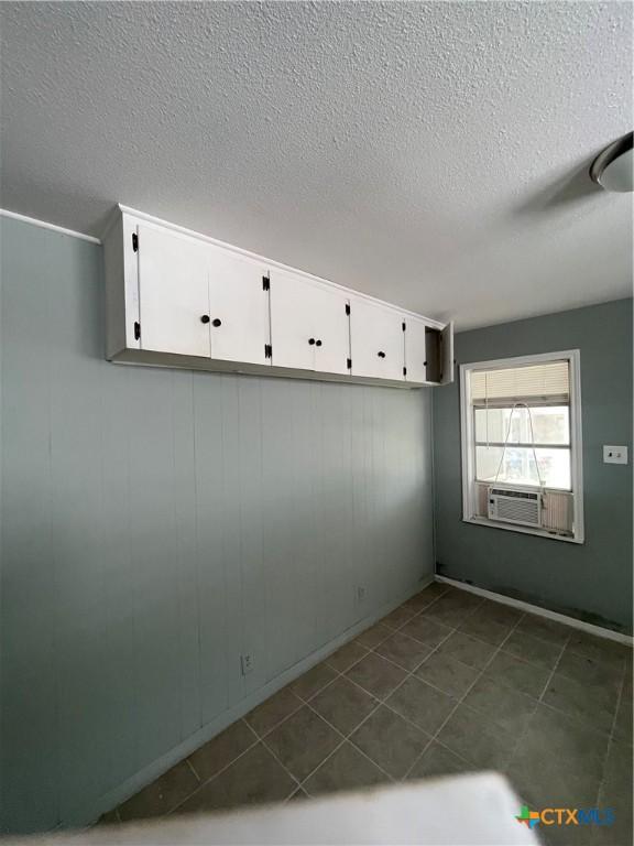 704 E 2nd St, Victoria, TX 77901 - empty room featuring a textured ceiling, cooling unit, and dark tile patterned floors