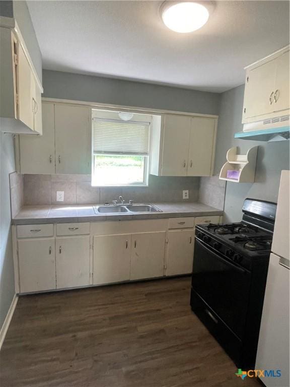 704 E 2nd St, Victoria, TX 77901 - kitchen featuring gas stove, under cabinet range hood, decorative backsplash, dark wood-style flooring, and refrigerator