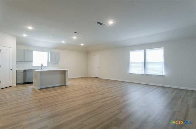 unfurnished living room featuring sink and light hardwood / wood-style flooring