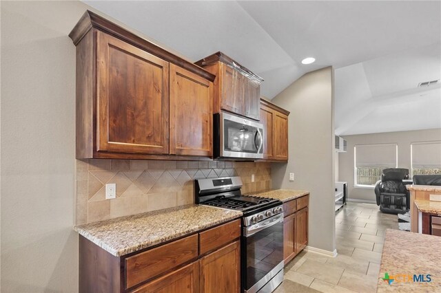 203 Terravista Trl, Victoria, TX 77904 - kitchen featuring appliances with stainless steel finishes, backsplash, open floor plan, light stone counters, and baseboards