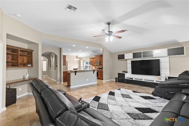 203 Terravista Trl, Victoria, TX 77904 - living room with arched walkways, ceiling fan, baseboards, and light stone finish flooring