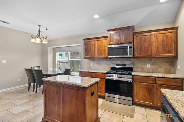 203 Terravista Trl, Victoria, TX 77904 - kitchen featuring appliances with stainless steel finishes, a kitchen island, decorative backsplash, a chandelier, and baseboards
