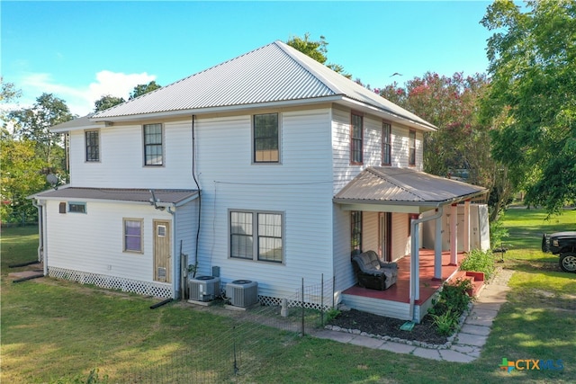 rear view of property featuring a lawn and central AC