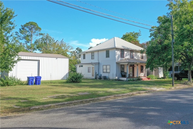 view of front of home with an outbuilding, a garage, cooling unit, and a front lawn