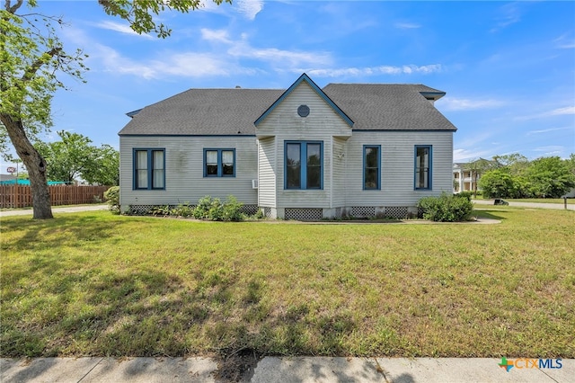 view of front of home with fence, roof with shingles, and a front lawn