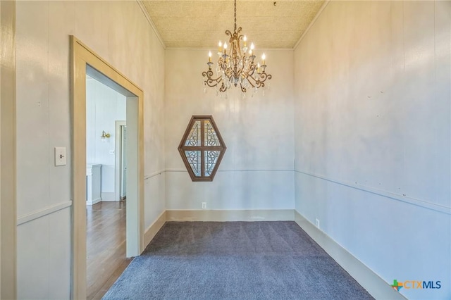 empty room featuring crown molding, a chandelier, and dark colored carpet