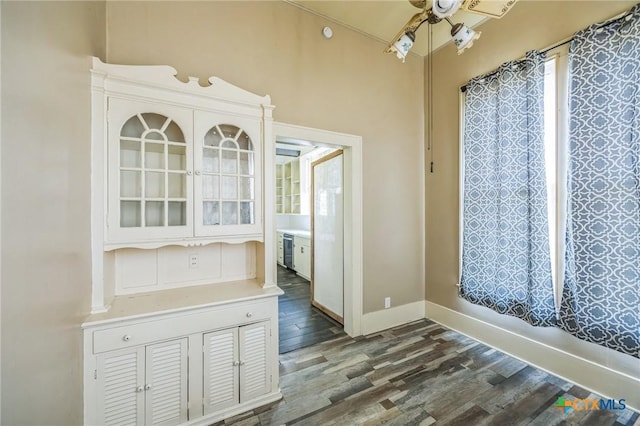 unfurnished dining area with ceiling fan, baseboards, and dark wood-type flooring
