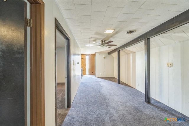 basement with visible vents, carpet flooring, and a ceiling fan