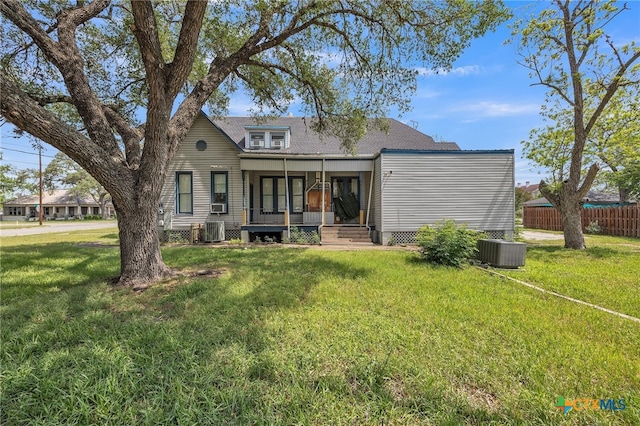 rear view of property featuring central AC unit, fence, and a yard