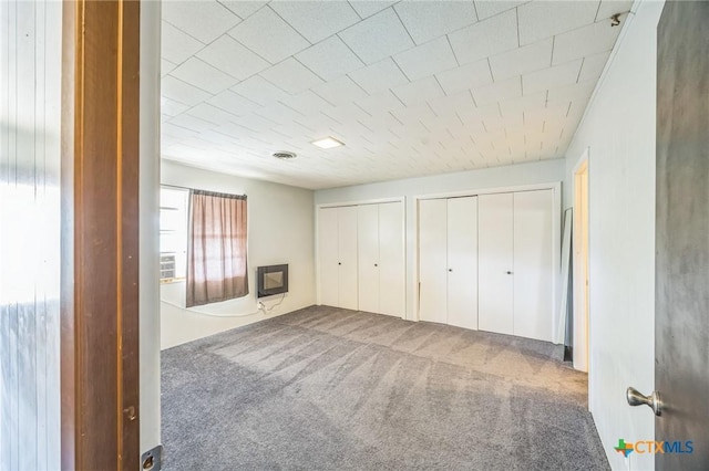 unfurnished bedroom with visible vents, carpet, and multiple closets