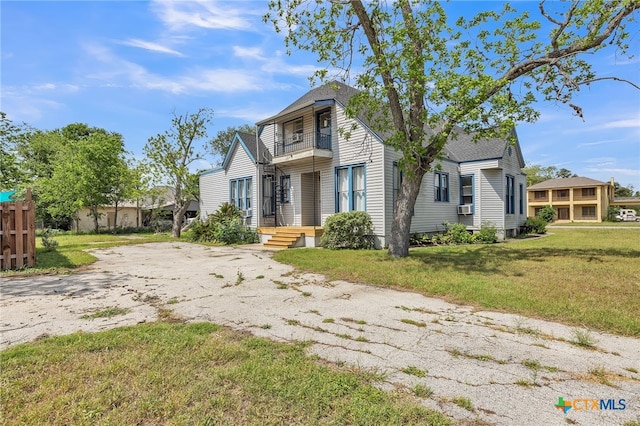 traditional home with roof with shingles, a residential view, cooling unit, a balcony, and a front lawn