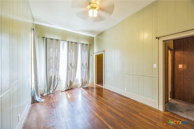 unfurnished room featuring a ceiling fan, baseboards, and hardwood / wood-style floors