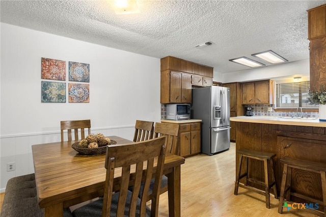 kitchen with stainless steel appliances, a sink, visible vents, light countertops, and light wood finished floors