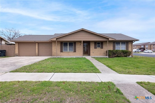 ranch-style home with a garage, concrete driveway, roof with shingles, a front lawn, and brick siding