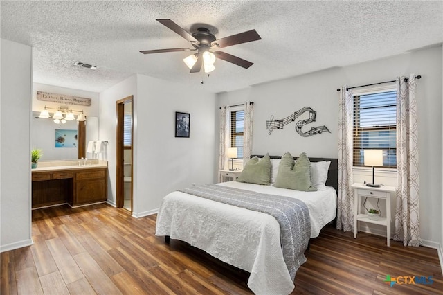 bedroom featuring a textured ceiling, wood finished floors, visible vents, baseboards, and a ceiling fan