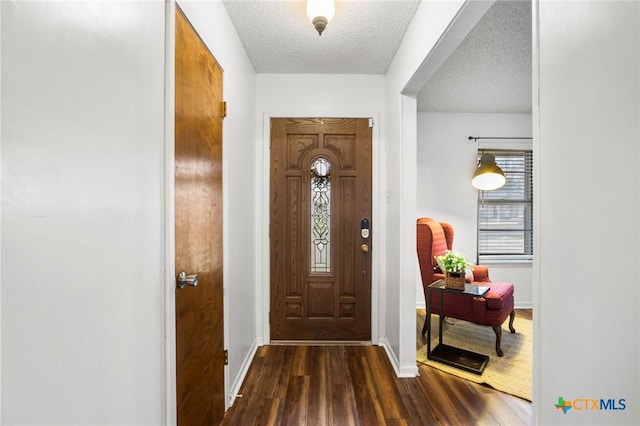 foyer with a textured ceiling, dark wood-type flooring, and baseboards