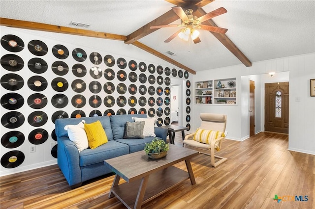 living room featuring visible vents, a textured ceiling, lofted ceiling with beams, and wood finished floors