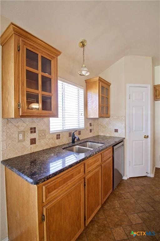 kitchen with a sink, dark stone countertops, tasteful backsplash, stainless steel dishwasher, and glass insert cabinets