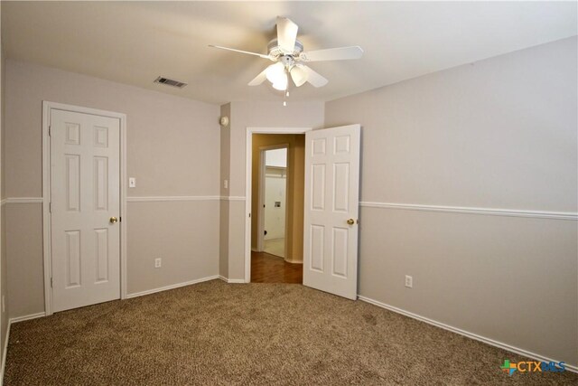 unfurnished bedroom with carpet, visible vents, and ceiling fan