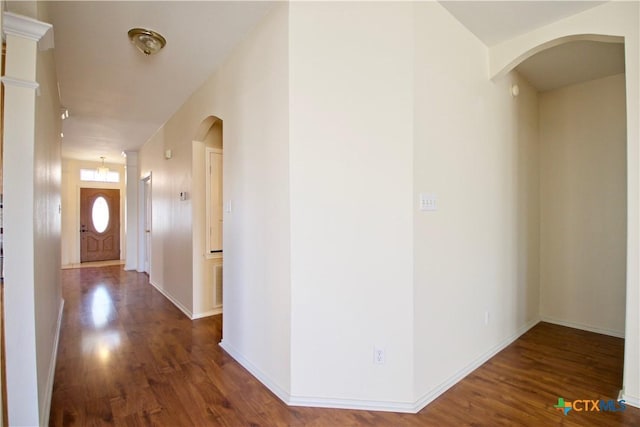 hallway with decorative columns, arched walkways, and wood finished floors