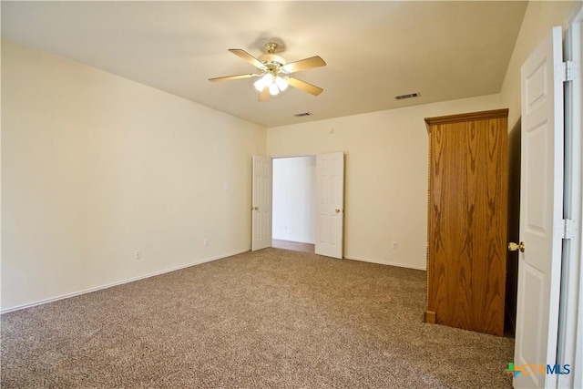 unfurnished bedroom featuring visible vents, ceiling fan, baseboards, and carpet