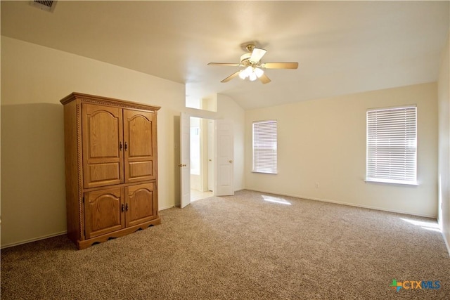 unfurnished bedroom featuring vaulted ceiling, multiple windows, visible vents, and light carpet