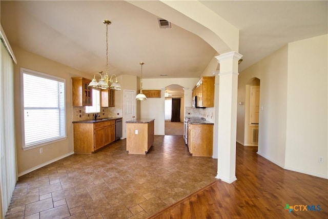 kitchen featuring arched walkways, a sink, decorative backsplash, stainless steel appliances, and a center island