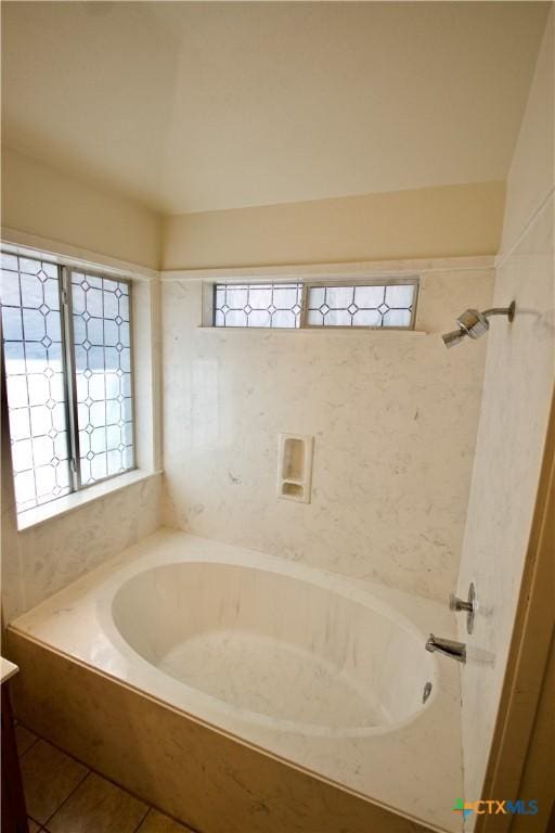 bathroom featuring tile patterned floors, a healthy amount of sunlight, and a tub to relax in