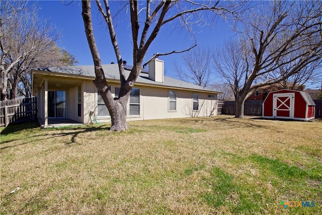 back of property featuring an outbuilding, a shed, a lawn, and fence