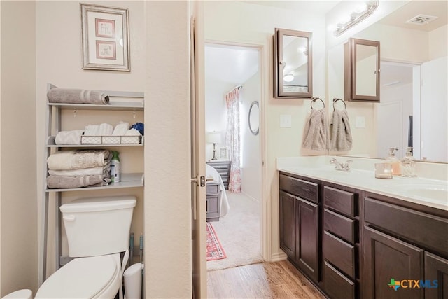 bathroom featuring wood-type flooring, toilet, and vanity