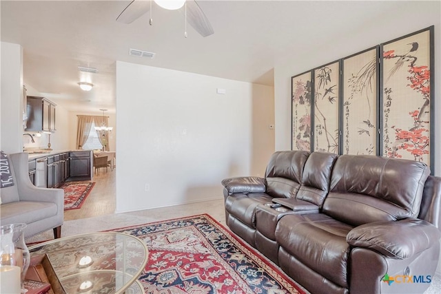 living room featuring ceiling fan with notable chandelier and sink