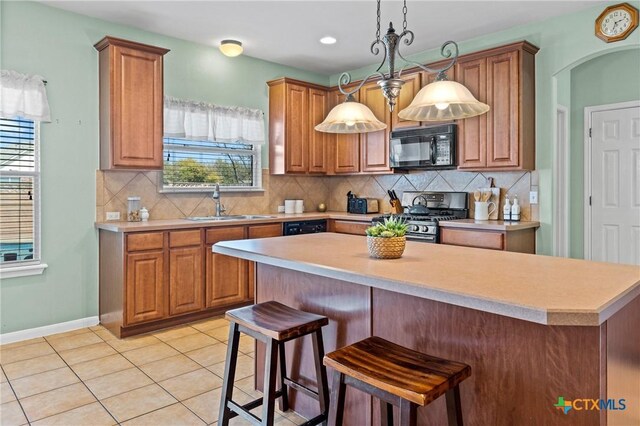 kitchen featuring light tile patterned floors, a sink, light countertops, black microwave, and stainless steel gas stove