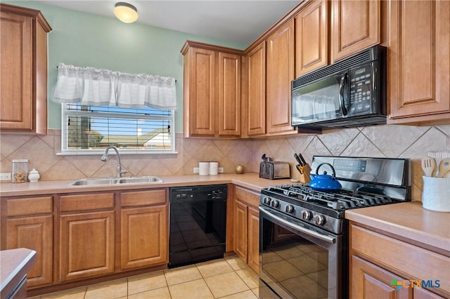 kitchen with tasteful backsplash, light countertops, brown cabinetry, black appliances, and a sink