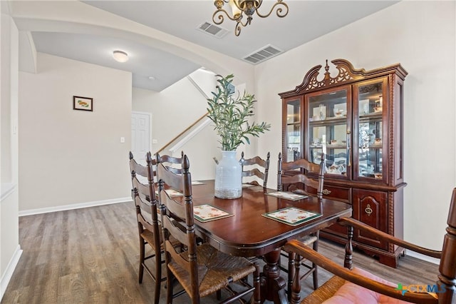 dining area featuring arched walkways, visible vents, baseboards, and wood finished floors